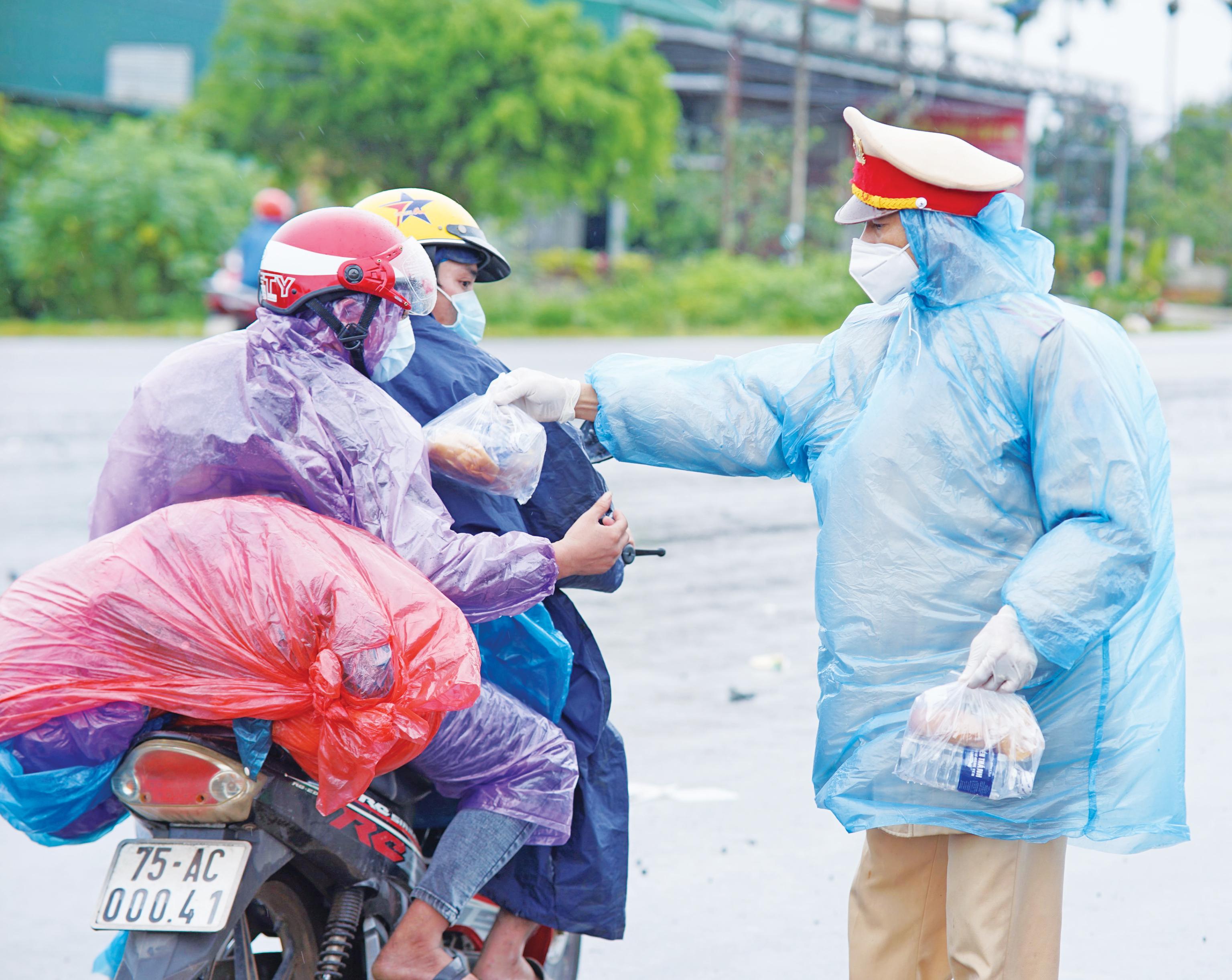 Chiến sĩ Cảnh sát Giao thông Công an tỉnh hỗ trợ thực phẩm cho người dân trên đường về quê tránh dịch. Ảnh: Phạm Quý