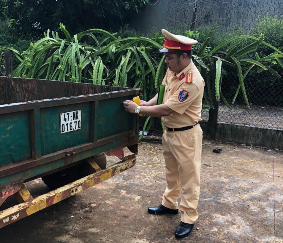 Cán bộ Đội Cảnh sát giao thông (Công an thị xã Buôn Hồ) dán decal phản quang cho xe công nông.