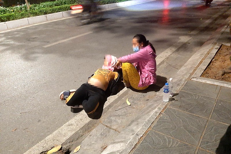 Hai phụ nữ nằm ngồi dưới lòng đường Lạc Long Quân xin sự thương cảm của những người qua lại