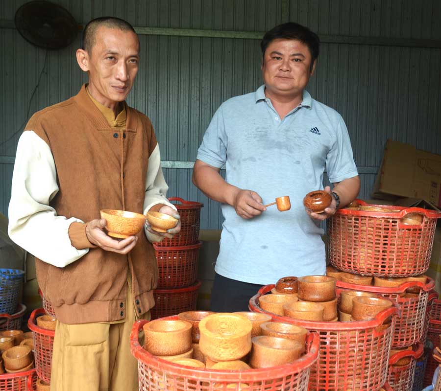 Ông Châu Công Minh (bên trái) giới thiệu các sản phẩm thủ công mỹ nghệ từ gỗ dừa. 