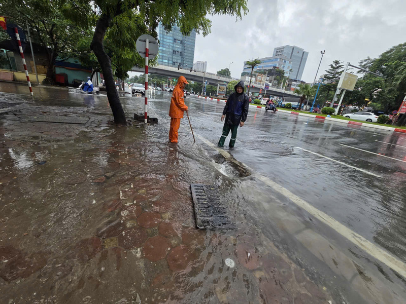 Người dân chủ động mở miệng cống để nước thoát nhanh hơn trên đường Hoàng Quốc Việt.