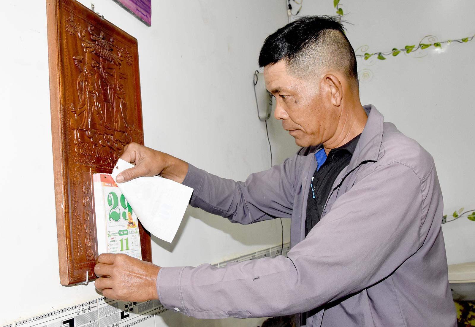 Anh Phạm Văn Tín, ngụ xã Thạnh Lộc gắn blốc lịch vào đốc lịch gỗ. Ảnh: KIỀU DIỄM