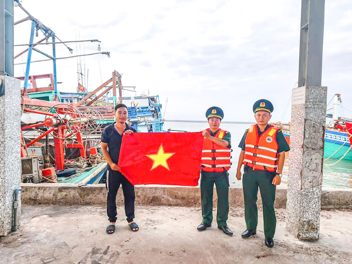 Bộ đội Biên phòng tặng cờ Tổ quốc cho ngư dân trước khi ra khơi. Ảnh: TRẦN QUỐC